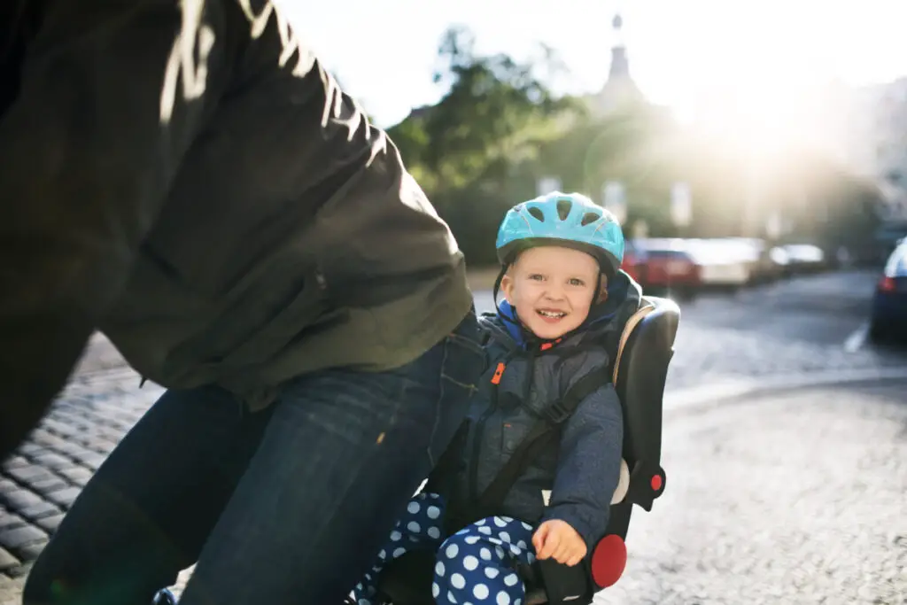 young child sitting in child bike seat smiling