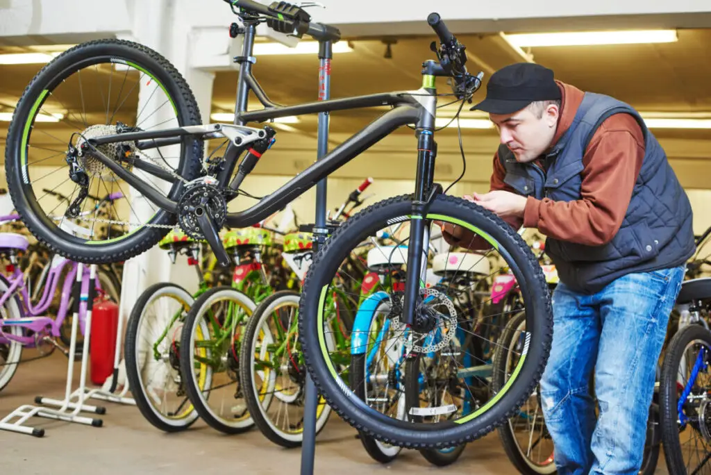 Bike maintenance: mechanic serviceman repairman installing assembling or adjusting bicycle gear on wheel in workshop